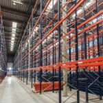 A large warehouse with bright lighting and rows of storage racks that nearly reach up to the ceiling.