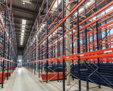 A large warehouse with bright lighting and rows of storage racks that nearly reach up to the ceiling.