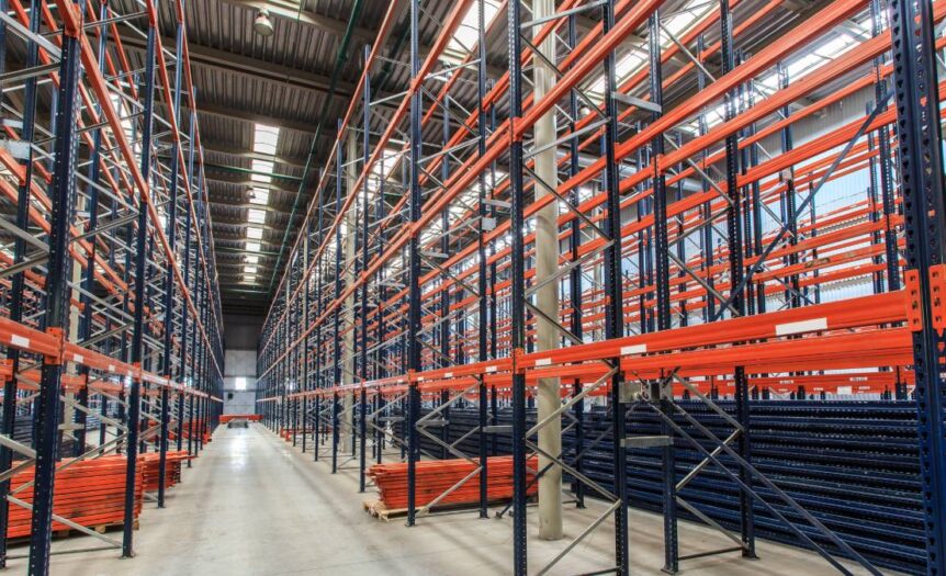 A large warehouse with bright lighting and rows of storage racks that nearly reach up to the ceiling.