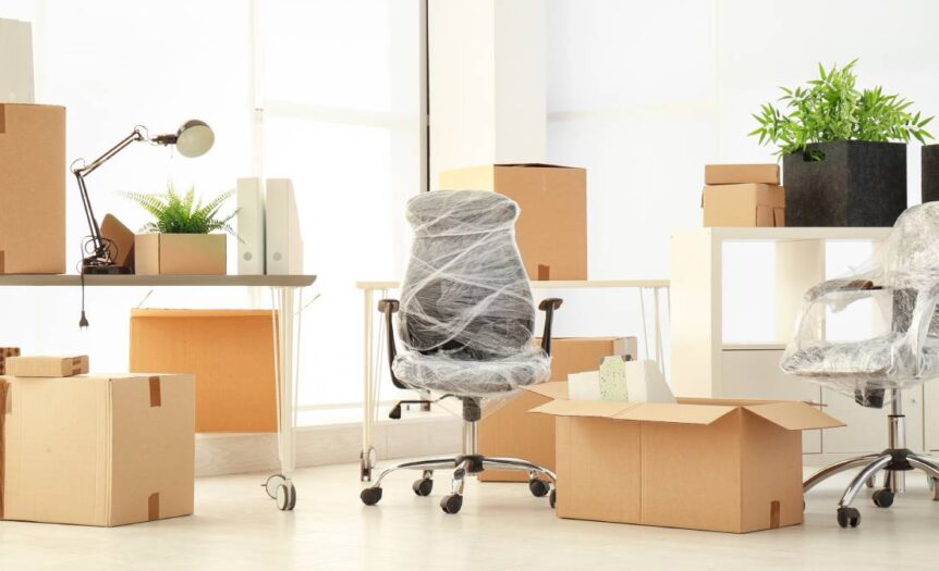 A newly furnished office space with moving boxes scattered around the space and the chairs wrapped in plastic.