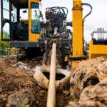 An industrial construction machine feeding a pipeline through an underground excavation via horizontal directional drilling.