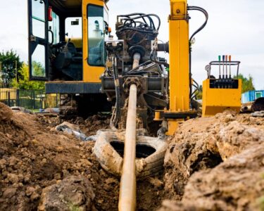 An industrial construction machine feeding a pipeline through an underground excavation via horizontal directional drilling.