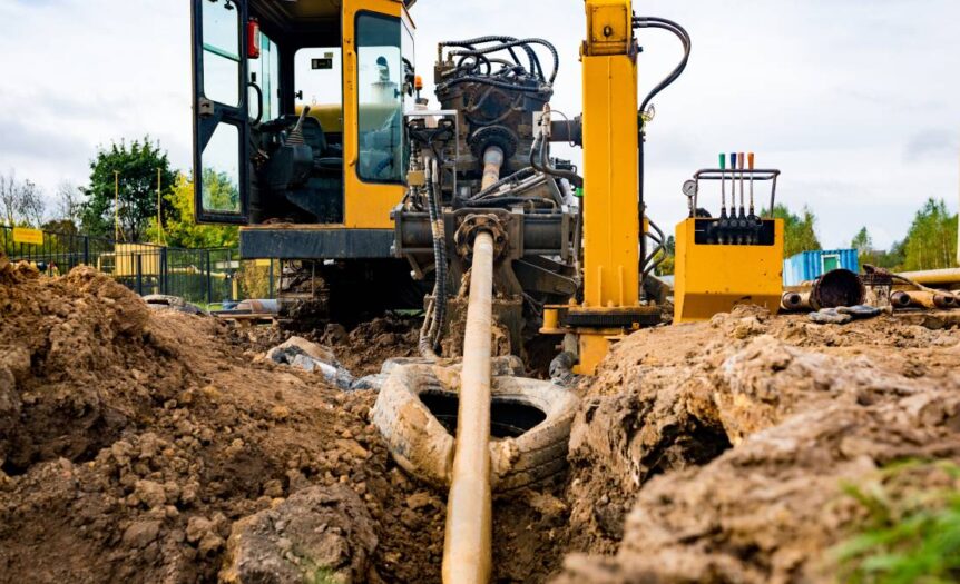 An industrial construction machine feeding a pipeline through an underground excavation via horizontal directional drilling.
