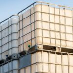 Rectangular white containers with metal frames stacked on top of one another with a blue sky in the background.