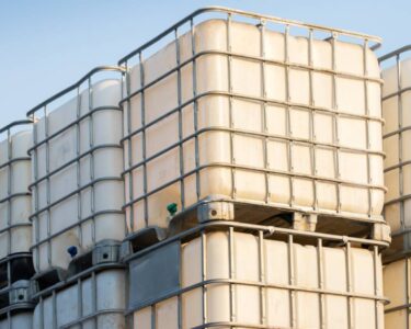 Rectangular white containers with metal frames stacked on top of one another with a blue sky in the background.