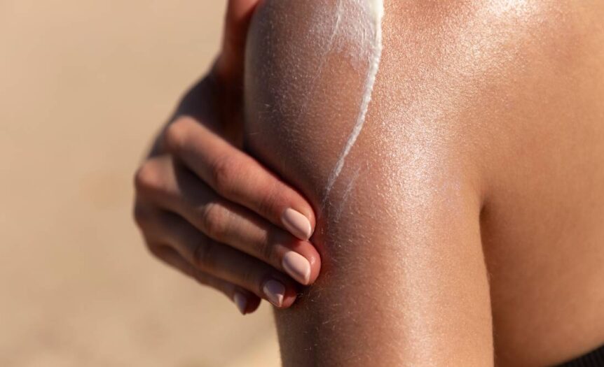 woman applying sunscreen to her shoulder to protect her skin for the sun