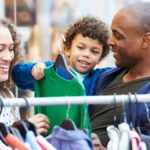 A mother, a father, and their young child browsing a selection of affordable kids’ clothing at a local store.