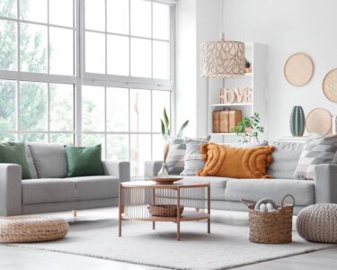 An open living room space with large windows that let in plentiful natural lighting. The furniture is organized.