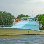 A boat with a new paint job of vibrant colors applied to its hull is surrounded by calm waves and a clear sky.