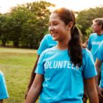 A group of people standing outside while wearing blue t-shirts with white lettering that says "Volunteer" across the chest.