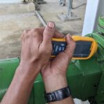 A man’s hands operating a portable vibration analysis device to maintain safety and efficiency in the industrial environment.