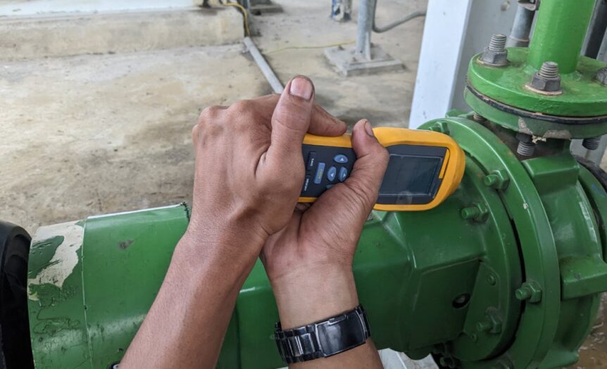 A man’s hands operating a portable vibration analysis device to maintain safety and efficiency in the industrial environment.