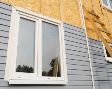 The exterior of a residential home under construction. The bottom half of the outdoor wall is covered with vinyl siding.