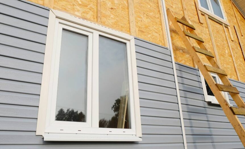 The exterior of a residential home under construction. The bottom half of the outdoor wall is covered with vinyl siding.