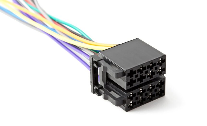 A black 8-cavity connector sits on a white surface with purple, orange, white, blue, red, green, and yellow wires.