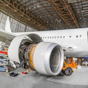 An airplane in a maintenance hanger—the composite plastic engine fuselage is open and receiving servicing.