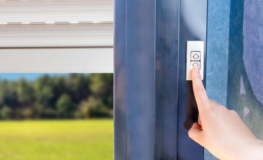 A person pushing a button labeled with a down arrow. Next to the button, a rolling shutter is partially lowered over a window.