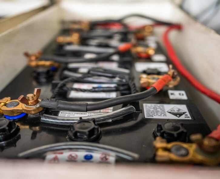 A boat battery exposed with black and red wiring attached to the connections. The connections are copper.