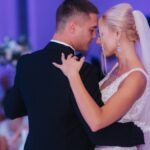 A young bride and groom dancing their first dance together on the dance floor in an indoor wedding venue.