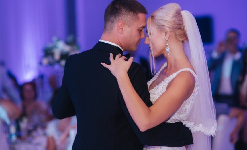 A young bride and groom dancing their first dance together on the dance floor in an indoor wedding venue.