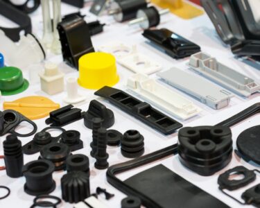 An assortment of plastic parts in varying shapes, textures, sizes, and colors organized on a white surface.