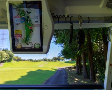 The inside of a golf cart that has a GPS map of the golf course grounds installed on the roof's frame.