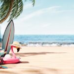 A sandy beach on a clear day. To the left is a blue vintage camper van, a beach chair, a guitar, and some flotation devices.