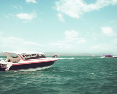 Four boats sit near each other on a large body of water. Large, fluffy clouds fill the blue summer sky.