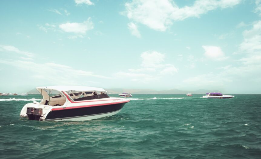 Four boats sit near each other on a large body of water. Large, fluffy clouds fill the blue summer sky.
