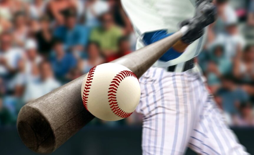 A close-up of playing using a dark brown bat to connect with a pristine white baseball with red stitching.