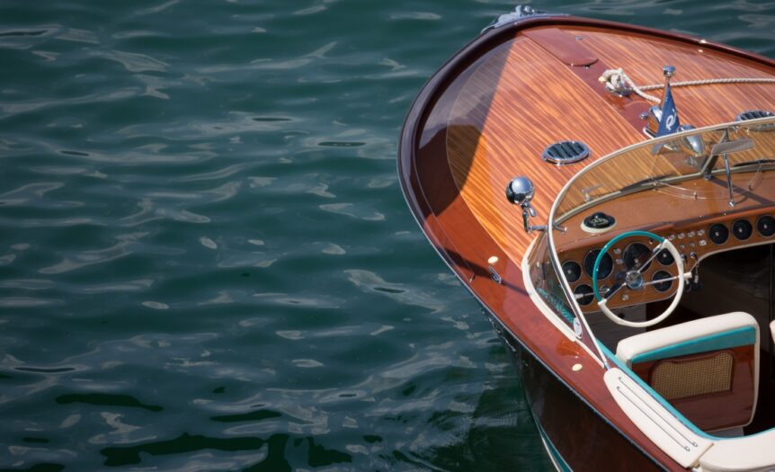 A luxurious, classic boat floats on open water. The bow showcases a polished wooden finish with timeless details.