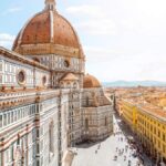 A sweeping view of the bustling cityscape outside the Dome of Santa Maria del Fiore church under a bright blue sky.