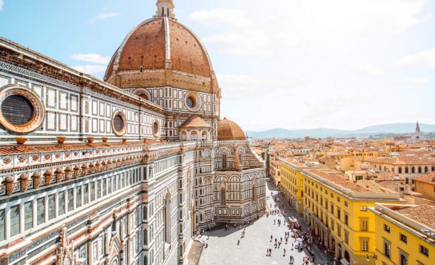 A sweeping view of the bustling cityscape outside the Dome of Santa Maria del Fiore church under a bright blue sky.