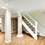 A freshly finished home basement with wood plank flooring, white baseboards, and light beige painted walls.
