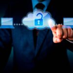 A man in a suit pointing at a graphic of two people connected by laptops and a cloud with an open lock.