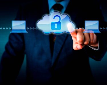 A man in a suit pointing at a graphic of two people connected by laptops and a cloud with an open lock.