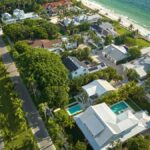 An aerial view of a small neighborhood. A beach is visible on the right and there are two main roads going through the area.