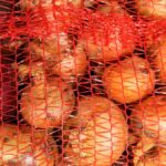A close-up of a package of onions still in their orange netting. The onions are yellow and red varieties.