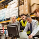 A group of people are gathered around a table. Two of them are wearing high visibility vests, while the other two are not.