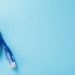 A blue Ethernet cable is coiled up to create a circle sitting partially in view. It sits on a teal background.