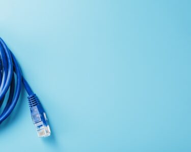A blue Ethernet cable is coiled up to create a circle sitting partially in view. It sits on a teal background.