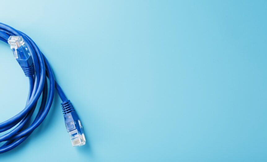 A blue Ethernet cable is coiled up to create a circle sitting partially in view. It sits on a teal background.