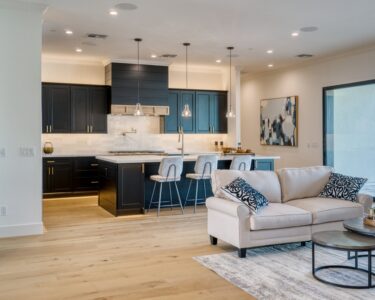 An open concept family home with a living room next to the kitchen space, separated by bar stools and a sofa.