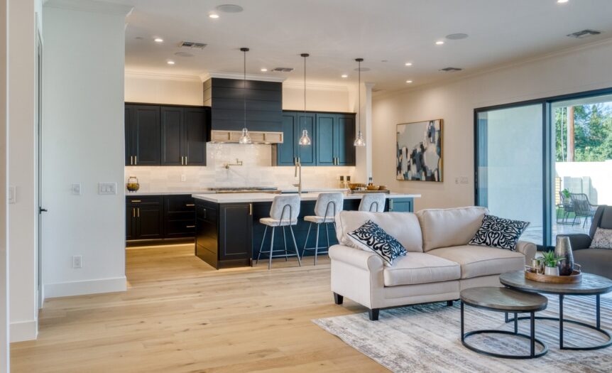 An open concept family home with a living room next to the kitchen space, separated by bar stools and a sofa.