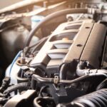 A car’s hood is open and the engine is exposed. There are multiple parts to the engine, with hoses and tubes coming out.