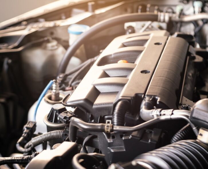 A car’s hood is open and the engine is exposed. There are multiple parts to the engine, with hoses and tubes coming out.