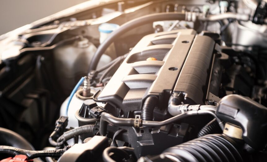 A car’s hood is open and the engine is exposed. There are multiple parts to the engine, with hoses and tubes coming out.
