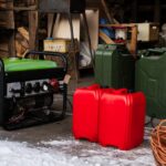 A green portable gas generator on a snowy driveway in front of an open garage stall next to two red gas cannisters.