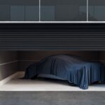 A car inside of a modern looking garage with a tarp over the top of it. A single camera points out from the garage wall.